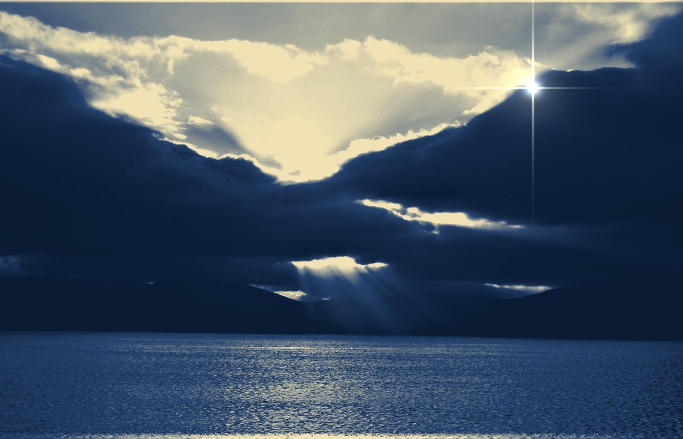 Sunlight breaking through dark clouds over water
